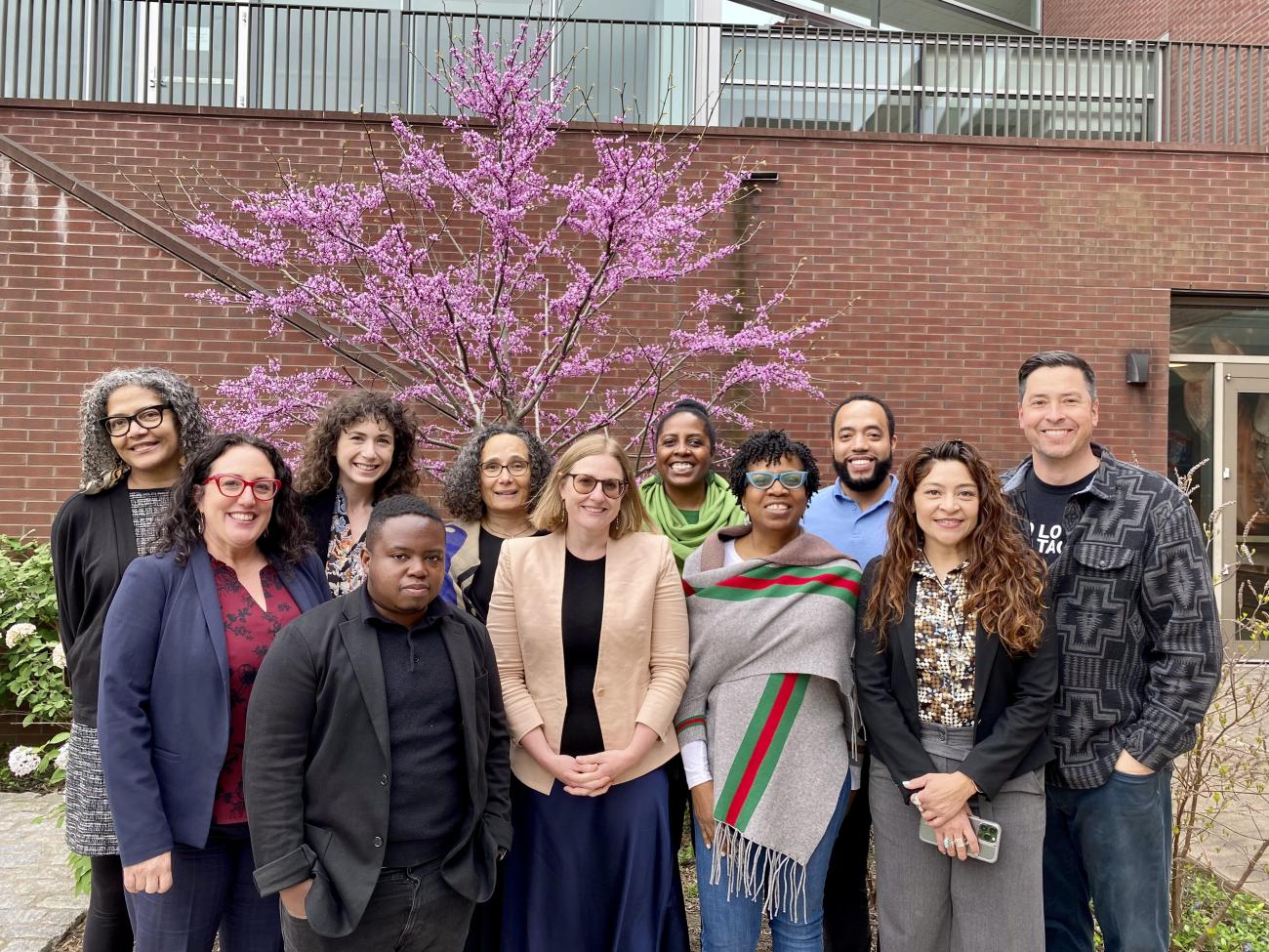 outdoor candid group photo with purple tree and brick wall