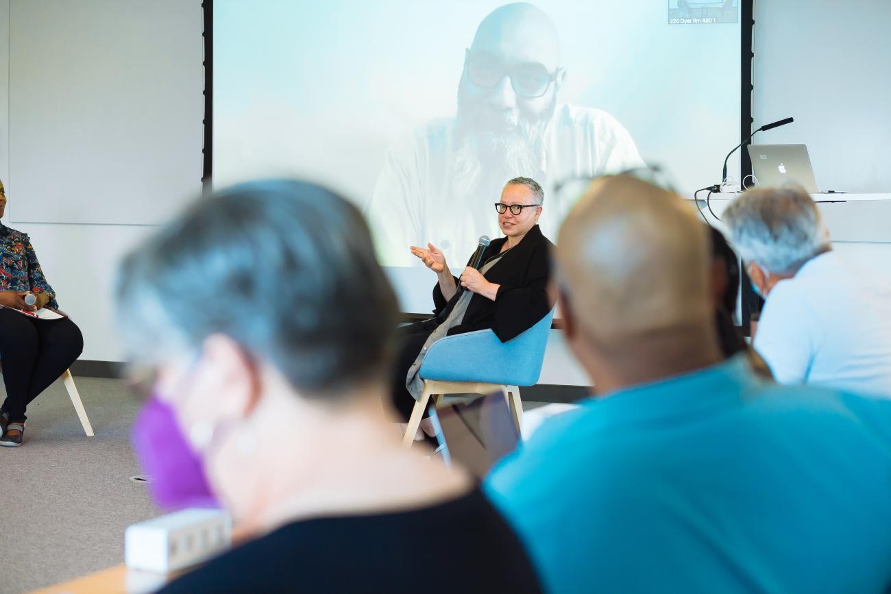 person with a microphone in a chair speaking to a group in a circle