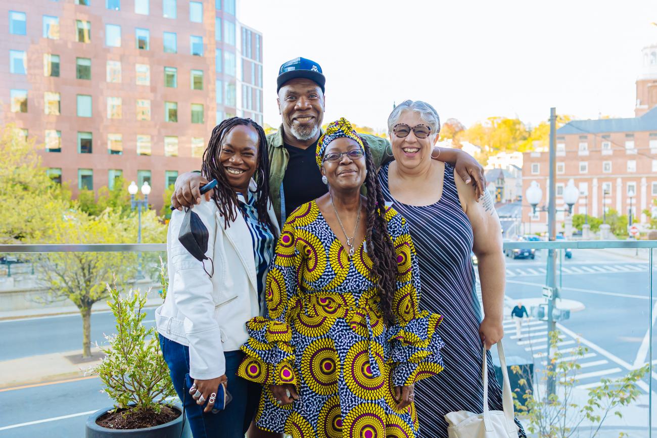 group of four smiling people of color posing for a photograph outside